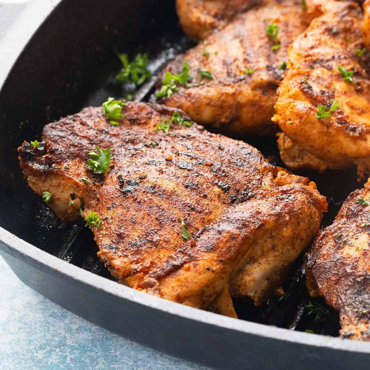 Grilled Chicken Thighs in a cast iron skillet with fresh herb garnish