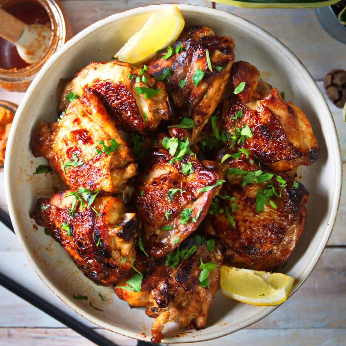 Korean Kimchi Chicken in a white bowl on a table with fresh slices of lemon.