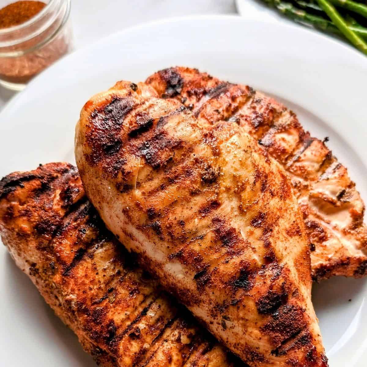 Low Sodium Grilled Chicken Recipe made and served on a white plate with dry rub spices and asparagus in the background.