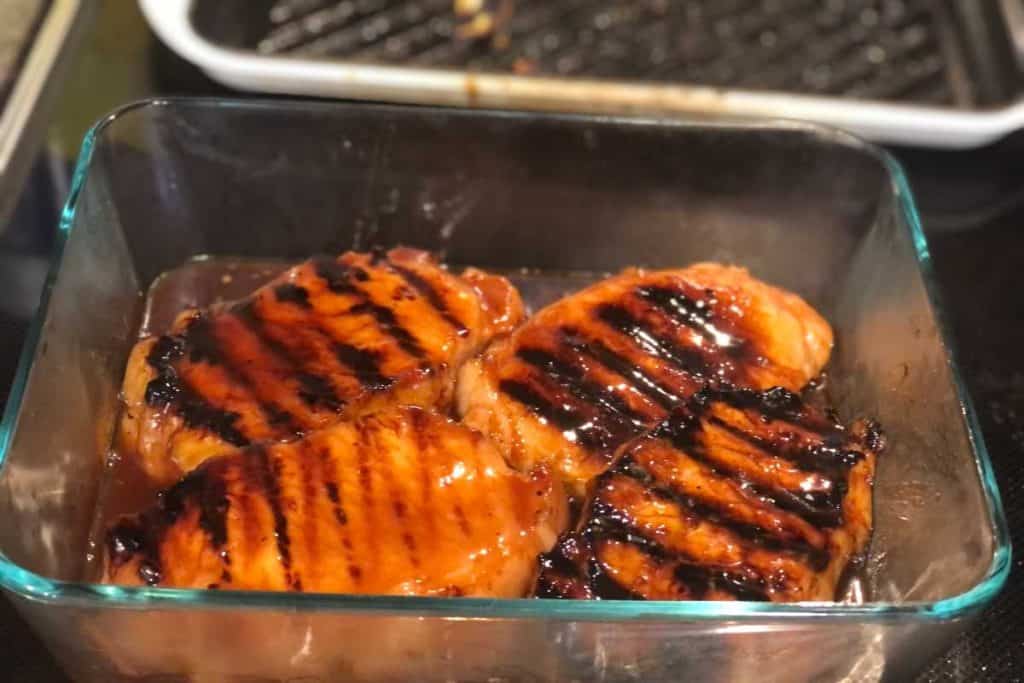 Grilled pork chops put in a glass baking dish and covered in bbq to finish cooking in the oven