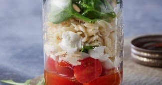 Italian Orzo Pasta Salad in a mason jar with tomatoes, mozzarella, orzo pasta and spinach with dressing in a jar.
