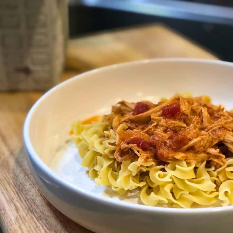 3-Jar Slow-Cooker Creamy Tomato Chicken served over egg noodles in a white bowl sitting on a wooden table