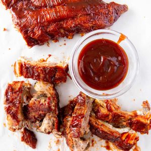 Juicy and tender baby back ribs cut up off the rack and served with a bowl of bbq sauce.