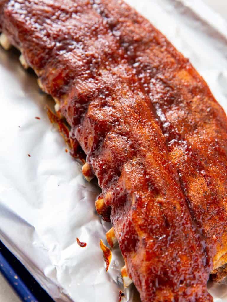 A rack of baby back ribs that has just come out from under the broiler and is caramelized and beautifully cooked