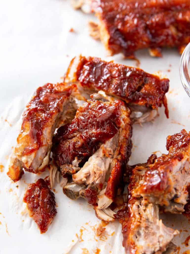 Sliced baby back ribs with the meat falling just off the bone on a white tablecloth