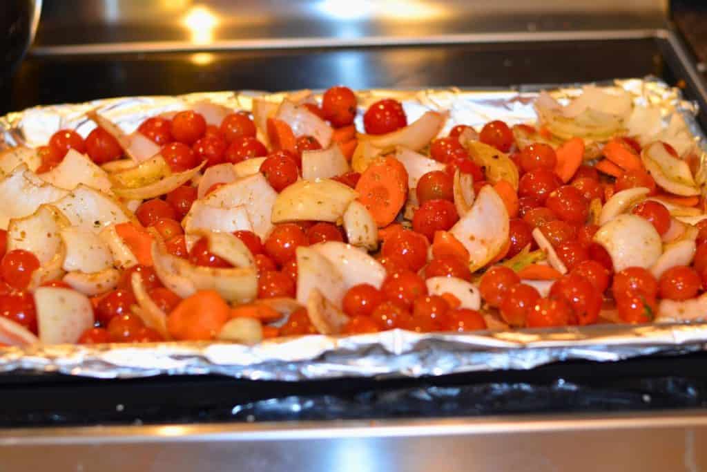 Carrots, onions and cherry tomatoes drizzled with balsamic vinegar and extra virgin olive oil and seasoned with salt, pepper, crushed red pepper and dried Italian seasoning, getting ready to go in the oven
