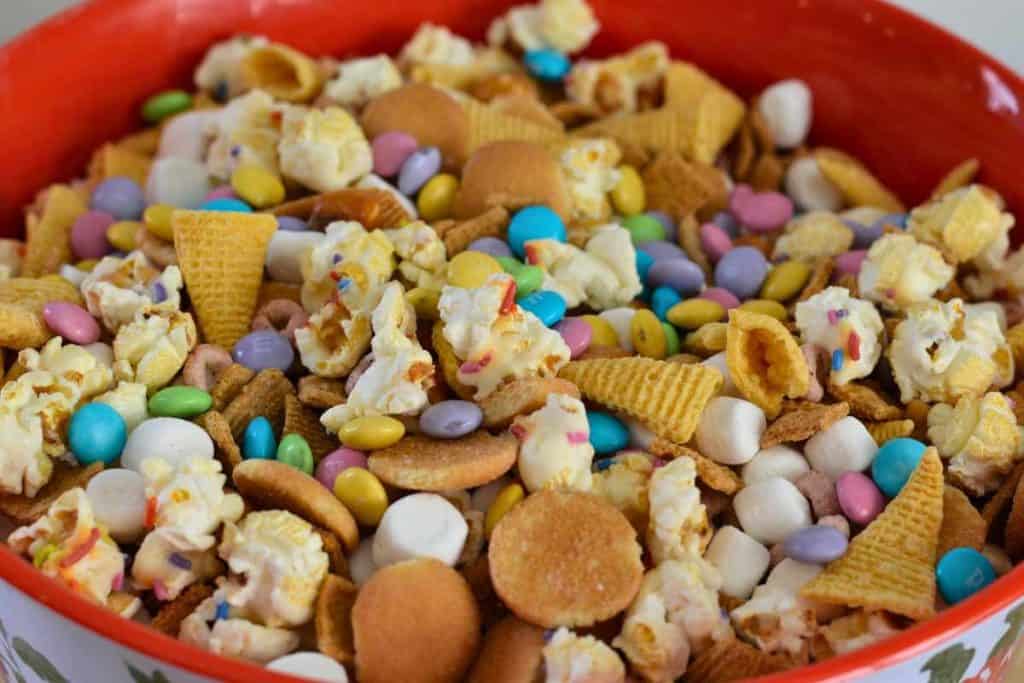 A bowl full of Easter Bunny Snack Mix including popcorn, chocolate candies, marshmallows and chips