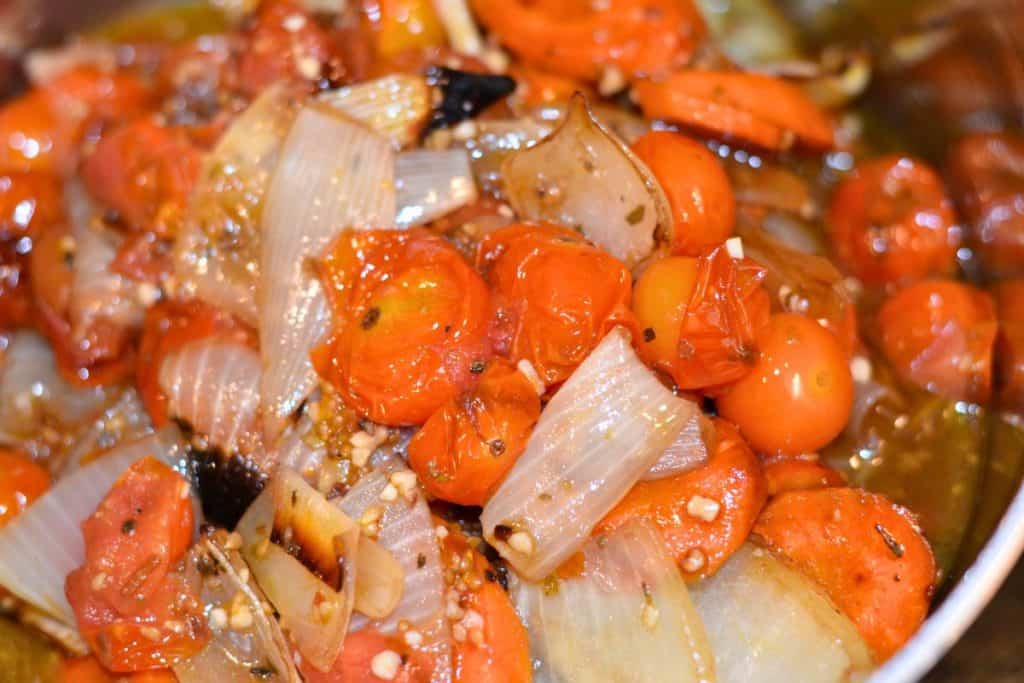 A close up of the finished roasted vegetables in the saucepan, including tomatoes, carrots and cherry tomatoes.