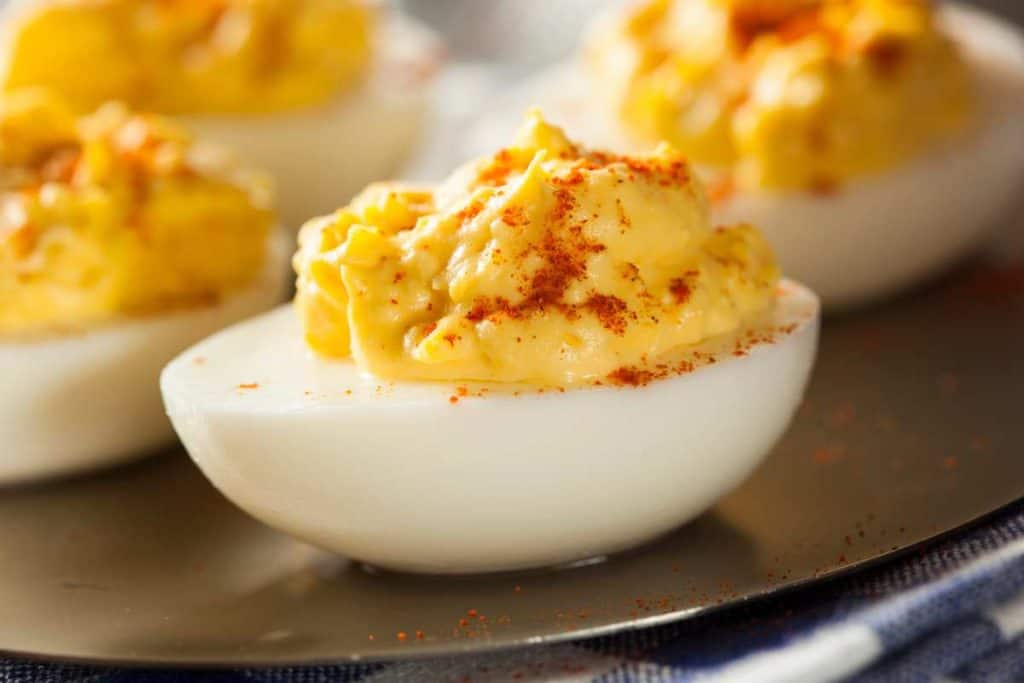 Stuffed deviled egg from the side, sprinkled with paprika on top