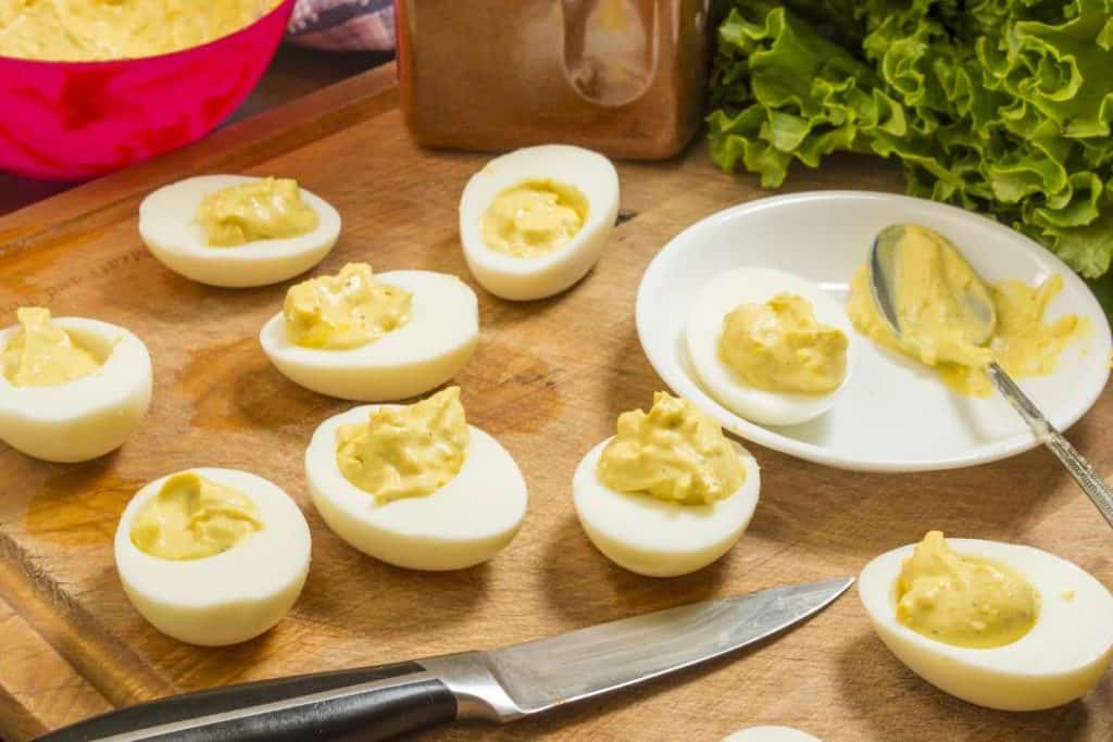 Deviled eggs on the cutting board being filled with filling