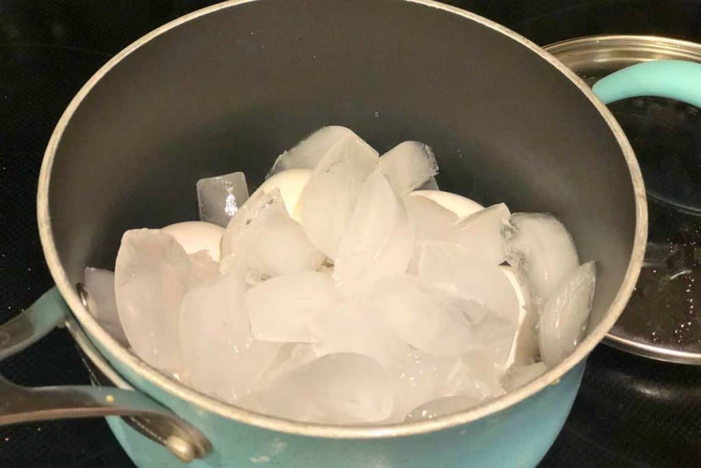 Pot of hard boiled eggs with ice on top of the eggs