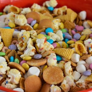 Close up of an Easter snack mix in a bowl with popcorn, chocolate candies, marshmallows and chips