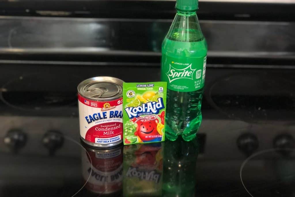 The 3 ingredients for lime kool aid ice cream including a Sprite bottle, a pack of lemon lime kool aid and a can of sweetened condensed milk