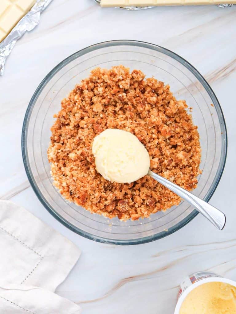 The bowl of crushed up cake crumbs with a spoon full of icing sitting on top, ready to be mixed in.