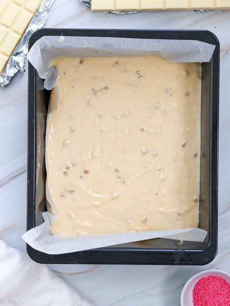 Cake batter in a rectangular pan lined with parchment paper ready to go into the oven to bake