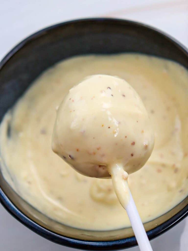 A round cake pop that has just been dunked in the white chocolate and is now completely coated.
