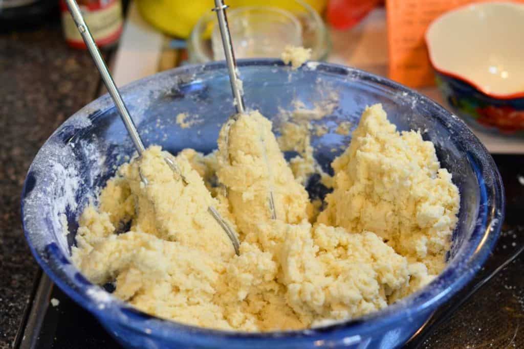 Snickerdoodle dough in a glass bowl with the mixer beaters sitting upright in the dough.