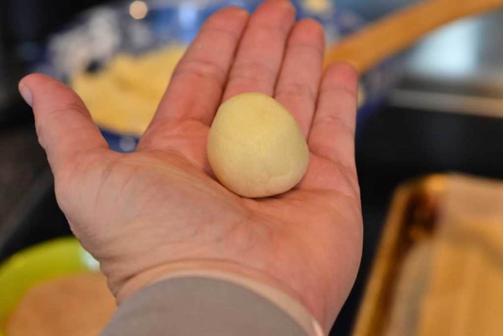 Snickerdoodle cookie dough rolled into a neat ball of dough in the palm of the baker's hand.