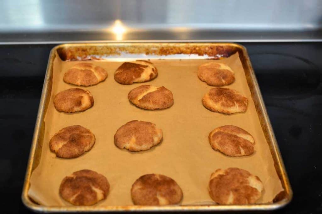 Snickerdoodle cookies right out of the oven lying on a baking sheet.