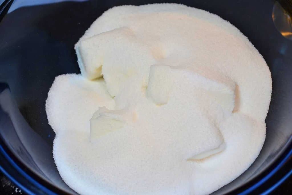 Sugar poured on top of cubes of shortening in a glass bowl