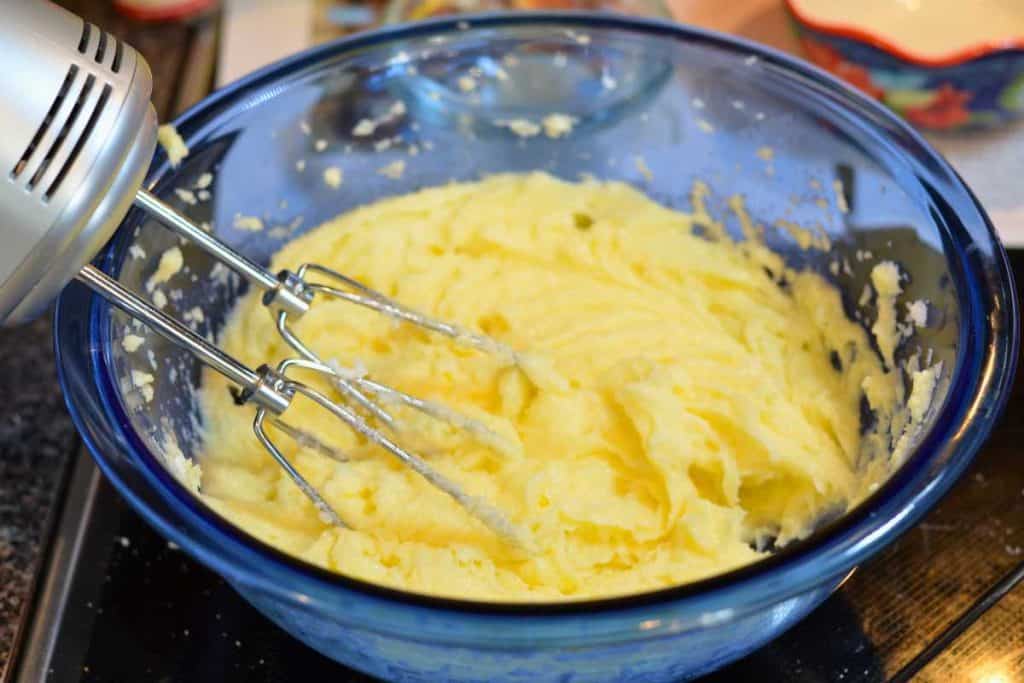 Eggs mixed in well with the sugar and shortening according to the Snickerdoodle recipe, in a blue glass bowl with a hand mixer.