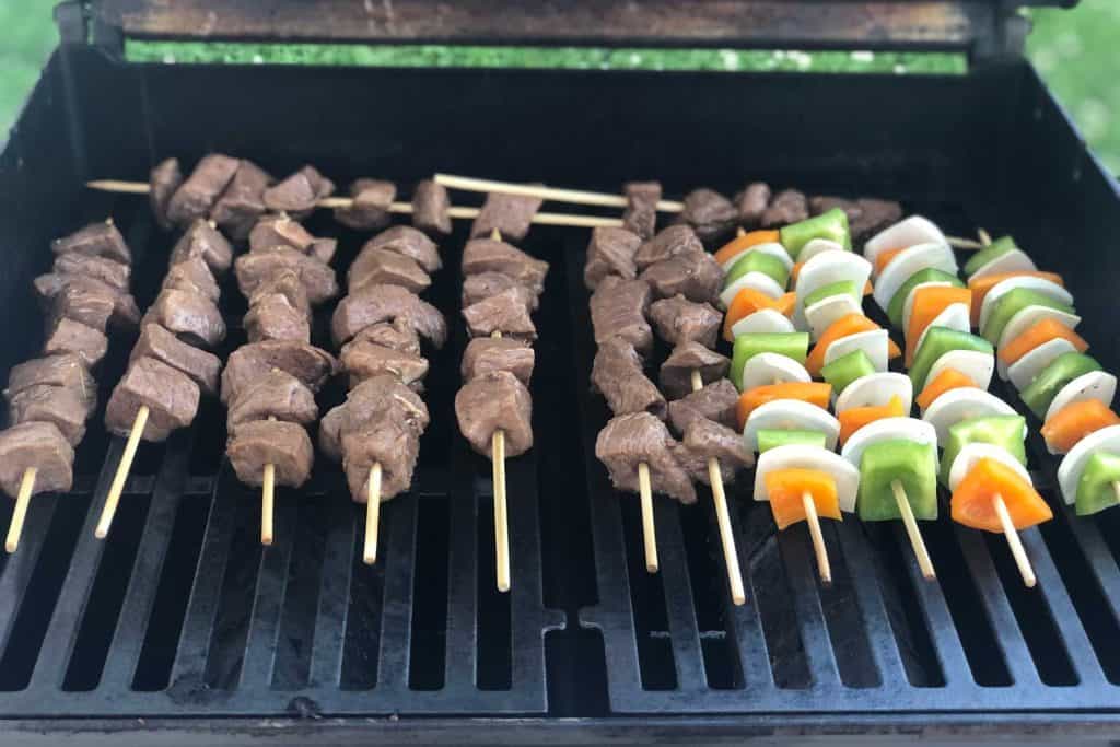 Steak and vegetable kebabs first put on the grill and cooking
