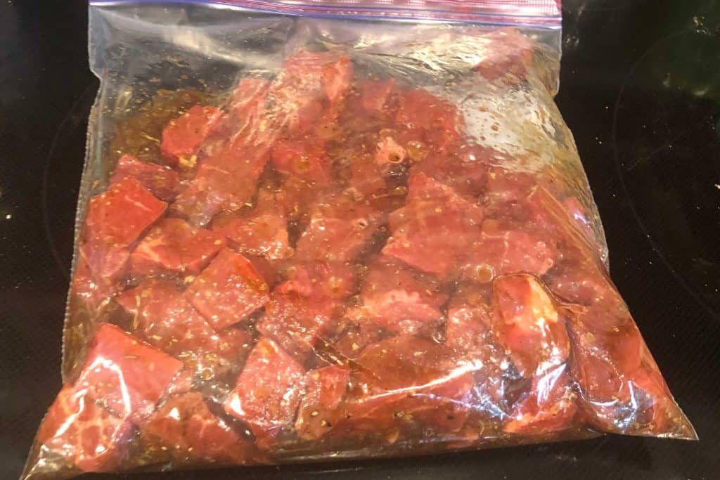 Steak cubed up and marinating in a Mediterranean mix marinade in a gallon-sized zip lock bag