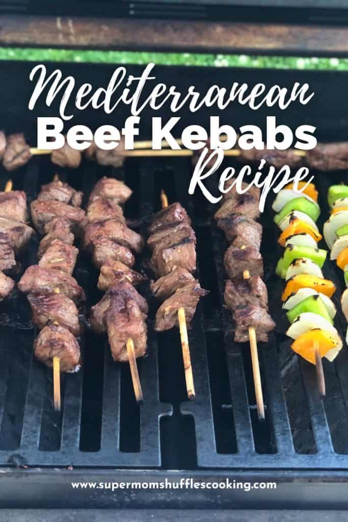 Pinterest graphic that says "Mediterranean Beef Kebabs Recipe" with the bckground being the beef and vegetable kebabs on the grill cooking