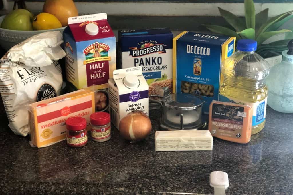 Ingredients for Smoked Cheddar Macaroni and Cheese including flour, half and half, panko, pasta, vegetable oil, smoked cheddar, salt, butter, heavy cream, onion, white pepper, chiptole pepper, medium cheddar.
