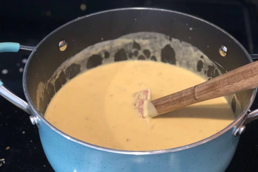 The sauce for Smoked Cheddar Macaroni and Cheese recipe in a large pot with a spatula stirring it