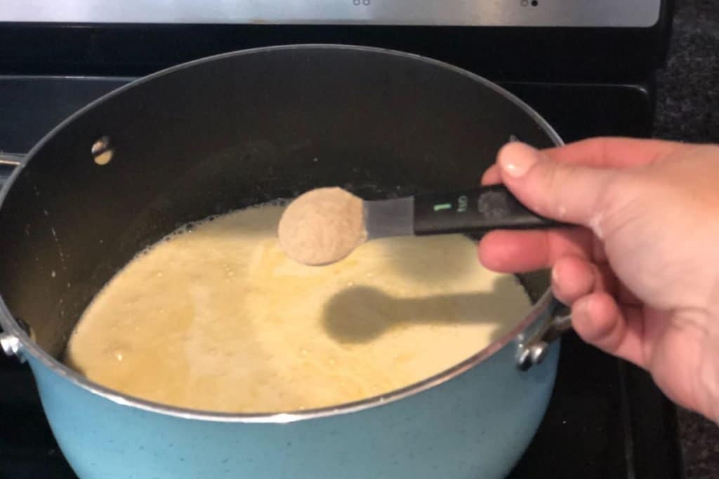 Adding white pepper to the sauce for Smoked Cheddar Macaroni and Cheese recipe