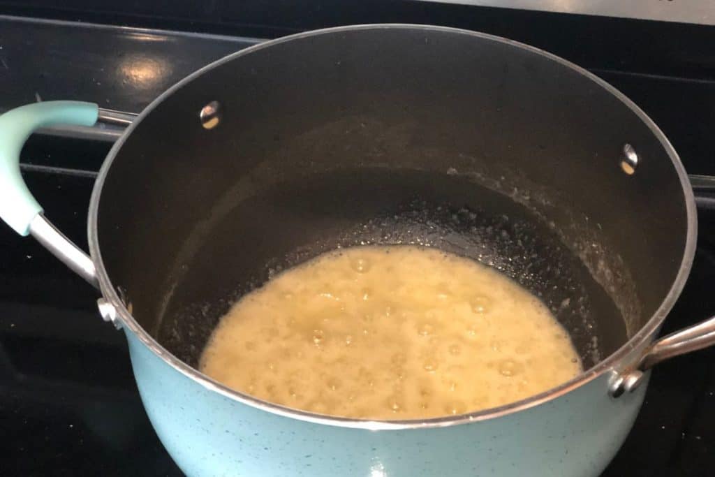A butter, onion and flour mixture bubbling in the bottom of a large pot, as part of Smoked Cheddar Macaroni and Cheese recipe