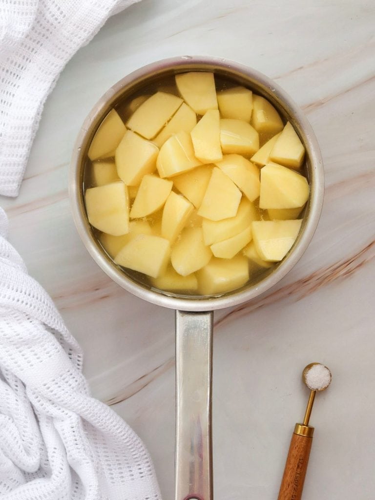 A saucepan filled with cubed potatoes in water