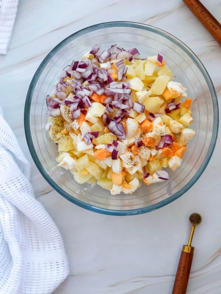 All the ingredients for potato salad in a glass mixing bowl