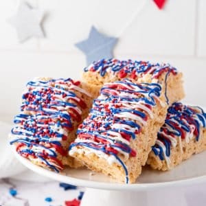 Patriotic red white and blue iced rice krispie treats on a plate.