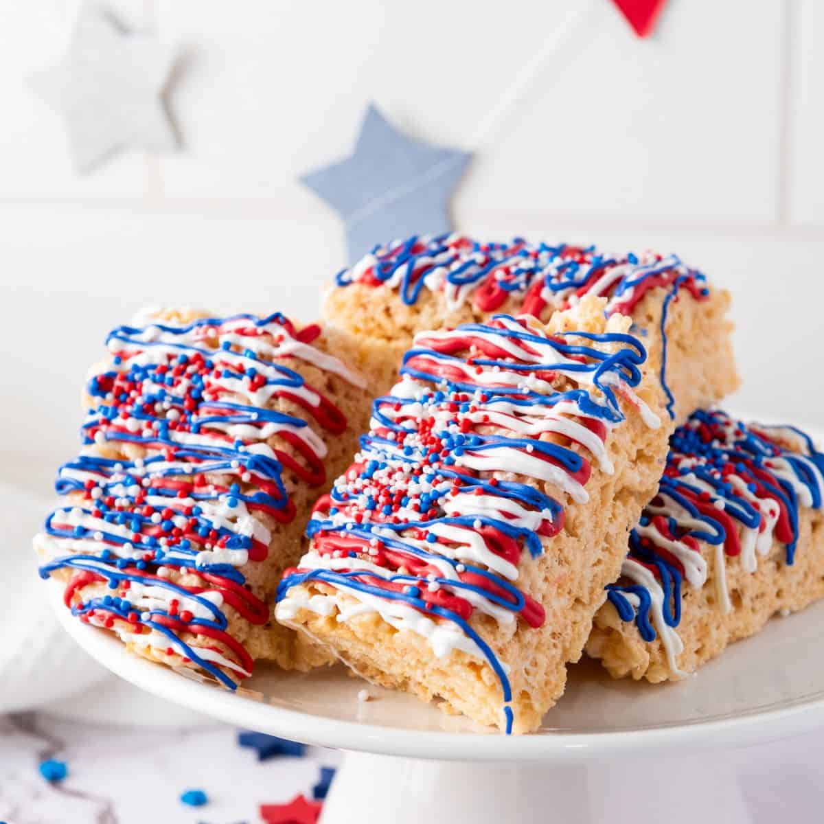 Patriotic red white and blue iced rice krispie treats on a plate.