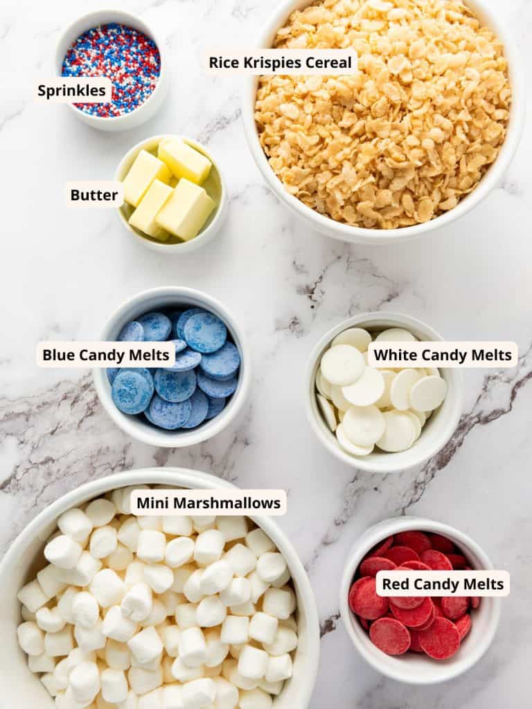 Ingredients for patriotic rice krispies including rice krispies, sprinkles, butter, candy melts in red, white and blue, and mini marshmallows