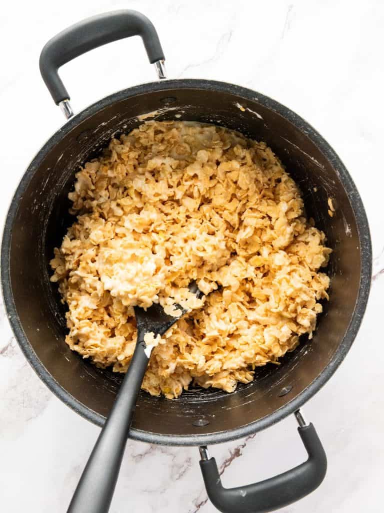rice krispies added to the melted butter and marshmallows as part of the process of making patriotic rice kripsies.