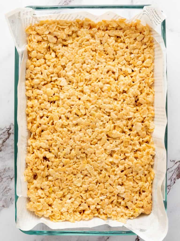 Rice krispy treats in a glass dish after being poured from the pan.