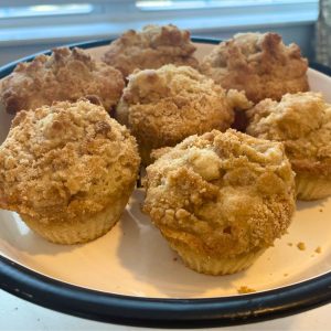 Apple cinnamon crumble streusel muffins on a platter in front of the window