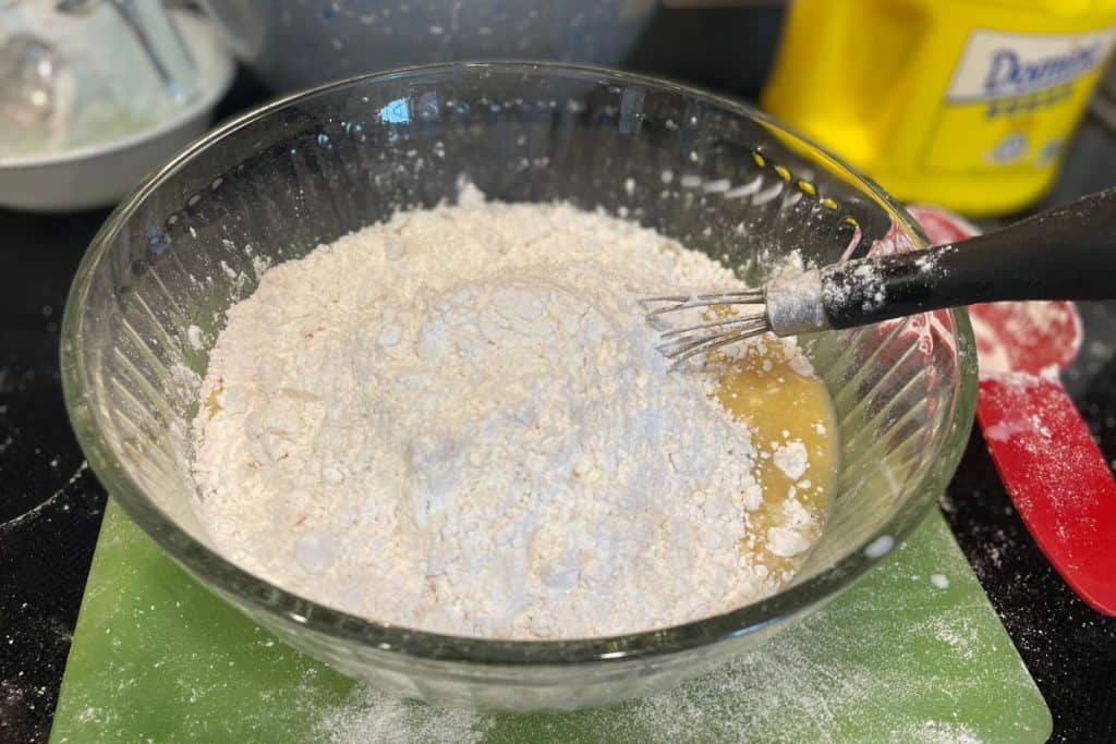 Flour added to the apple cinnamon muffin batter mixture with a flat whisk