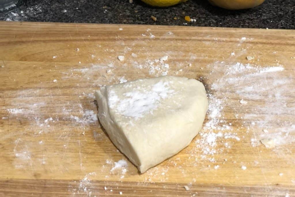 A portion of the homemade pie dough with a sprinkle of flour on top, waiting to be rolled out.