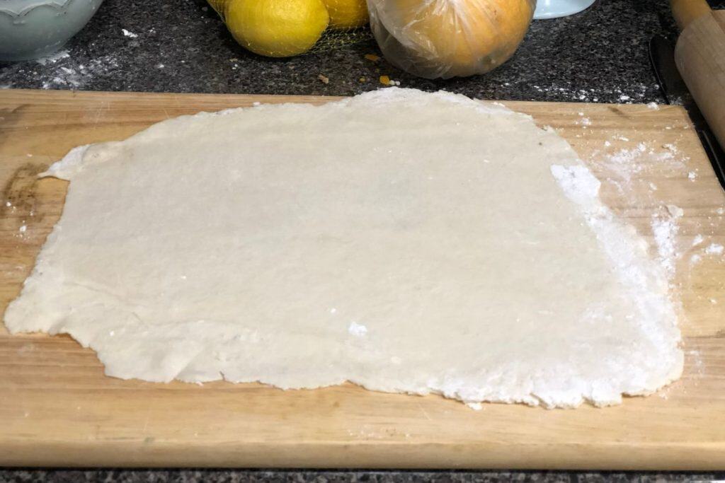 pie crust dough rolled out on a wooden cutting board to about a quarter inch thickness