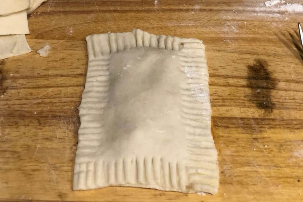 raw homemade pop tart on a cutting board with the edges crimped together