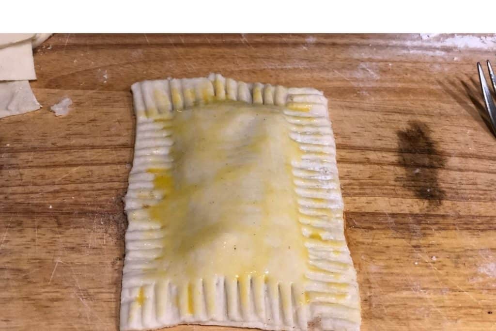 Egg wash brushed on top of the pie dough as part of the assembly of the homemade brown sugar cinnamon pop tarts