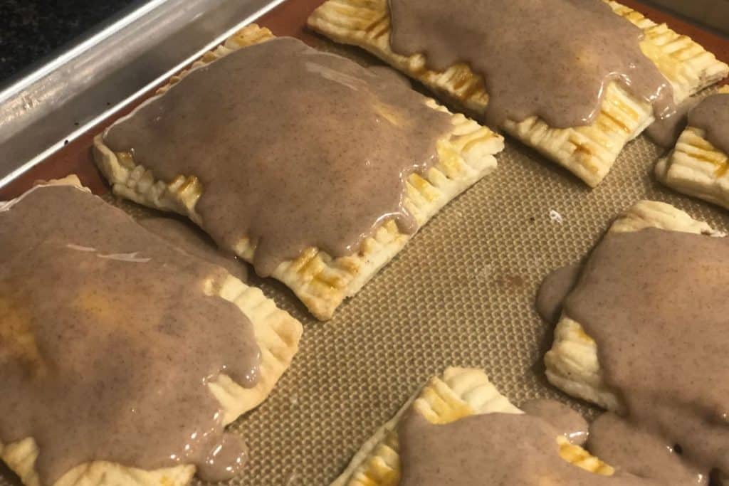 Homemade brown sugar cinnamon pop tarts iced and on a baking sheet cooling down.