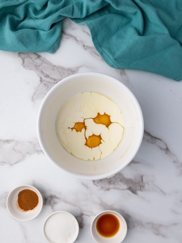 Egg mixture in a white bowl with heavy cream added to the eggs.