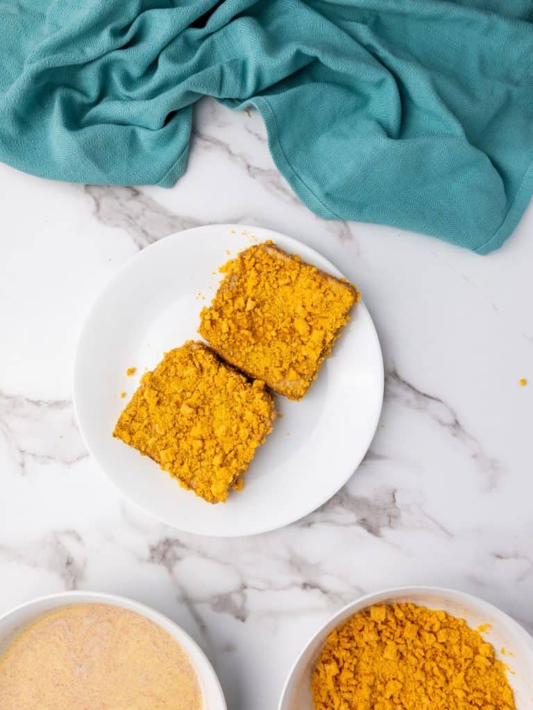Two pieces of thick sliced bread that have been coated with crushed Captain Crunch Cereal for the French Toast recipe