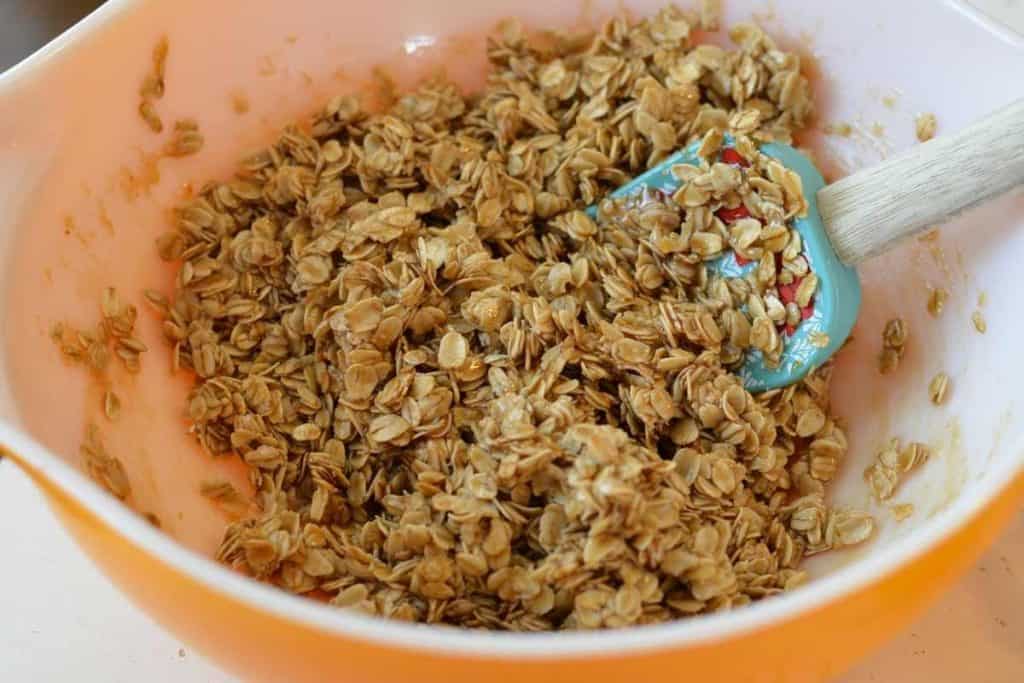 toasted oats covered in the granola bar sweet mixture in a bowl