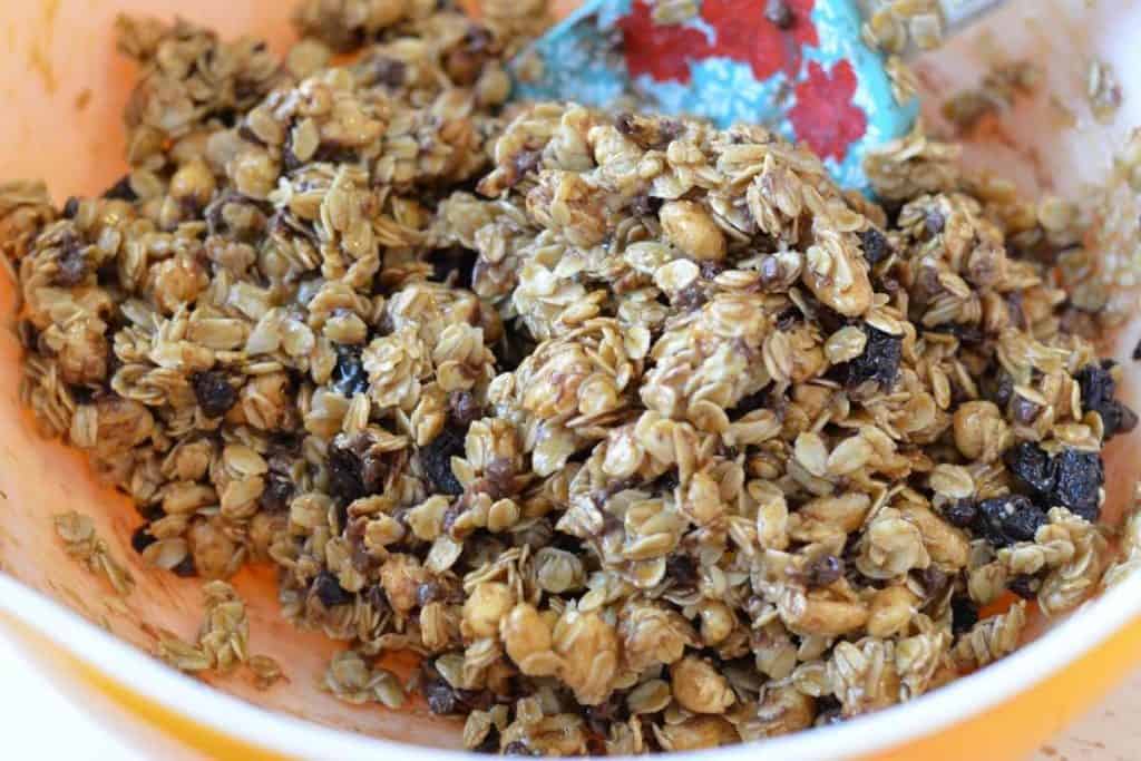 The granola mixture all mixed up in a bowl with a spatula